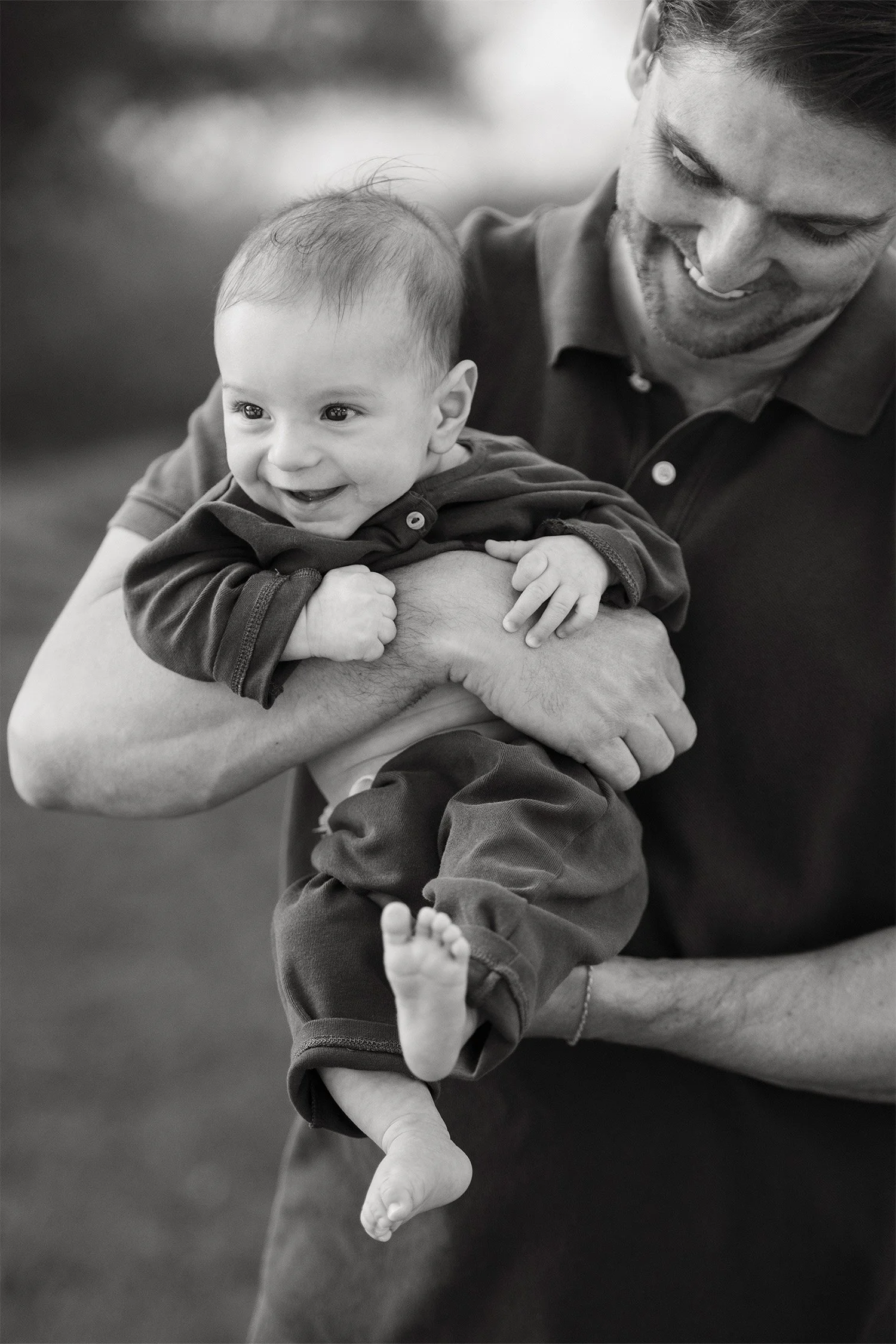 Highly recommended family photographer in Orange County photographs father laughing with his smiling baby son