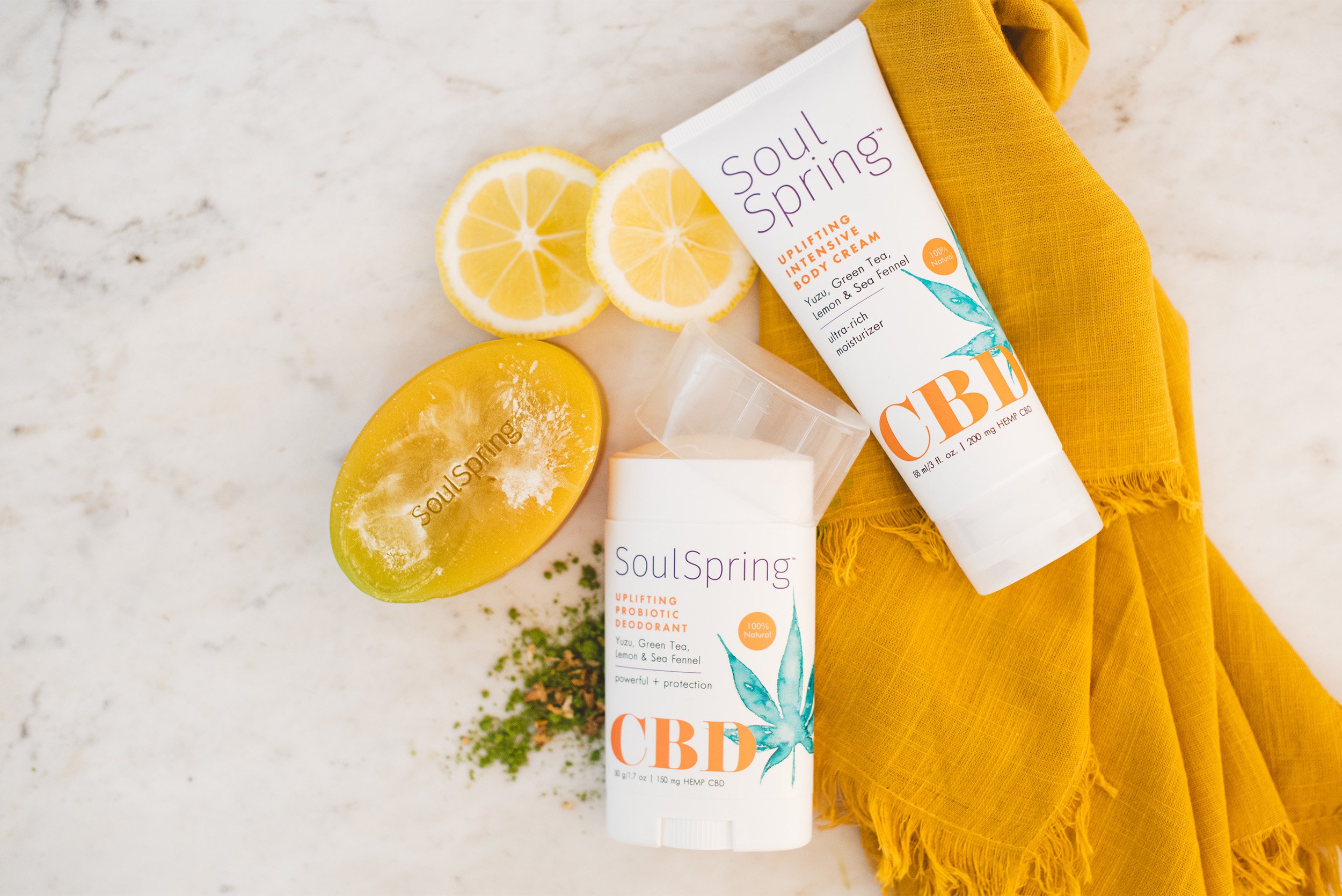 Product photography flatlay featuring SoulSpring CBD skincare line with lemon slices and yellow linen, Orange County product photographer