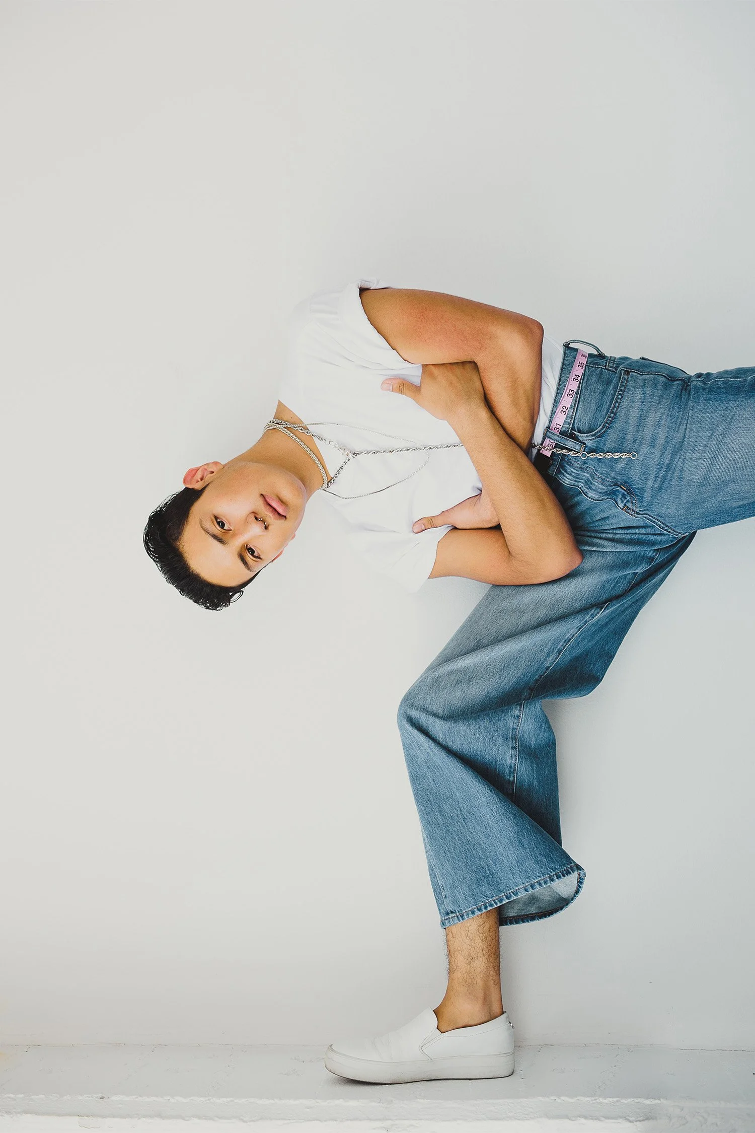Award-winning lifestyle photographer captures editorial-style portrait with denim and layered necklace styling against minimalist backdrop