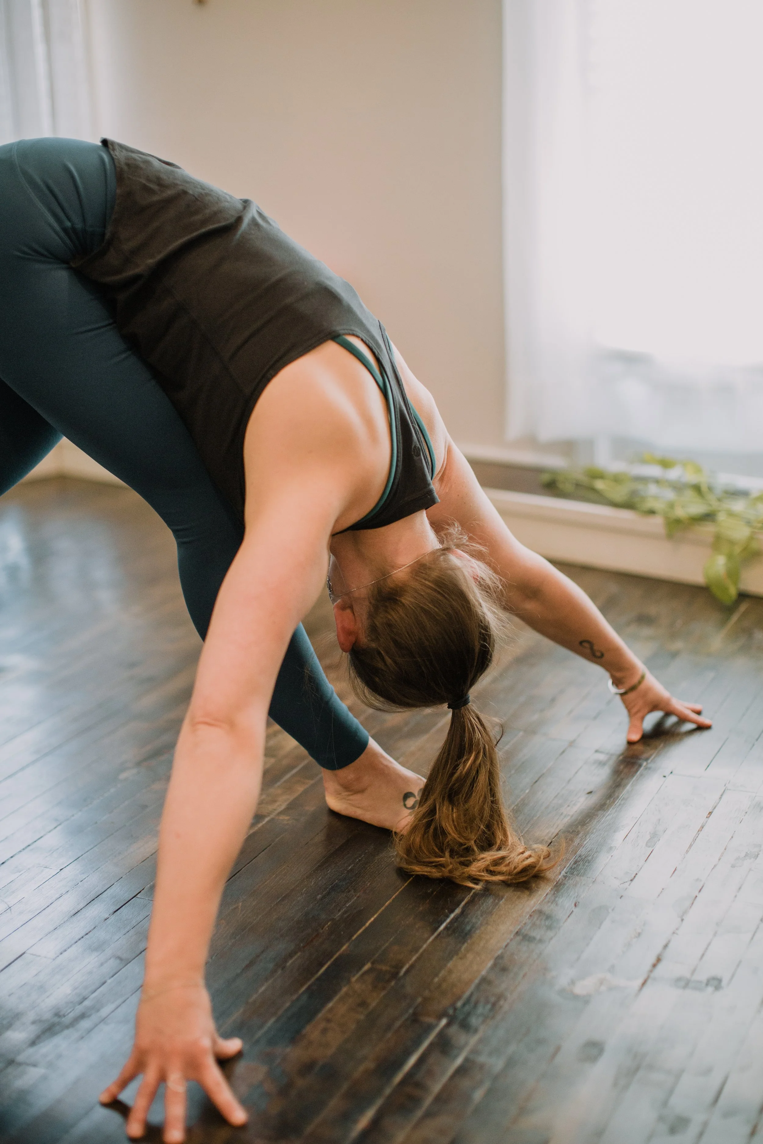 Woman doing a yoga forward bend pose  to increase flexibility on a yoga class near me.