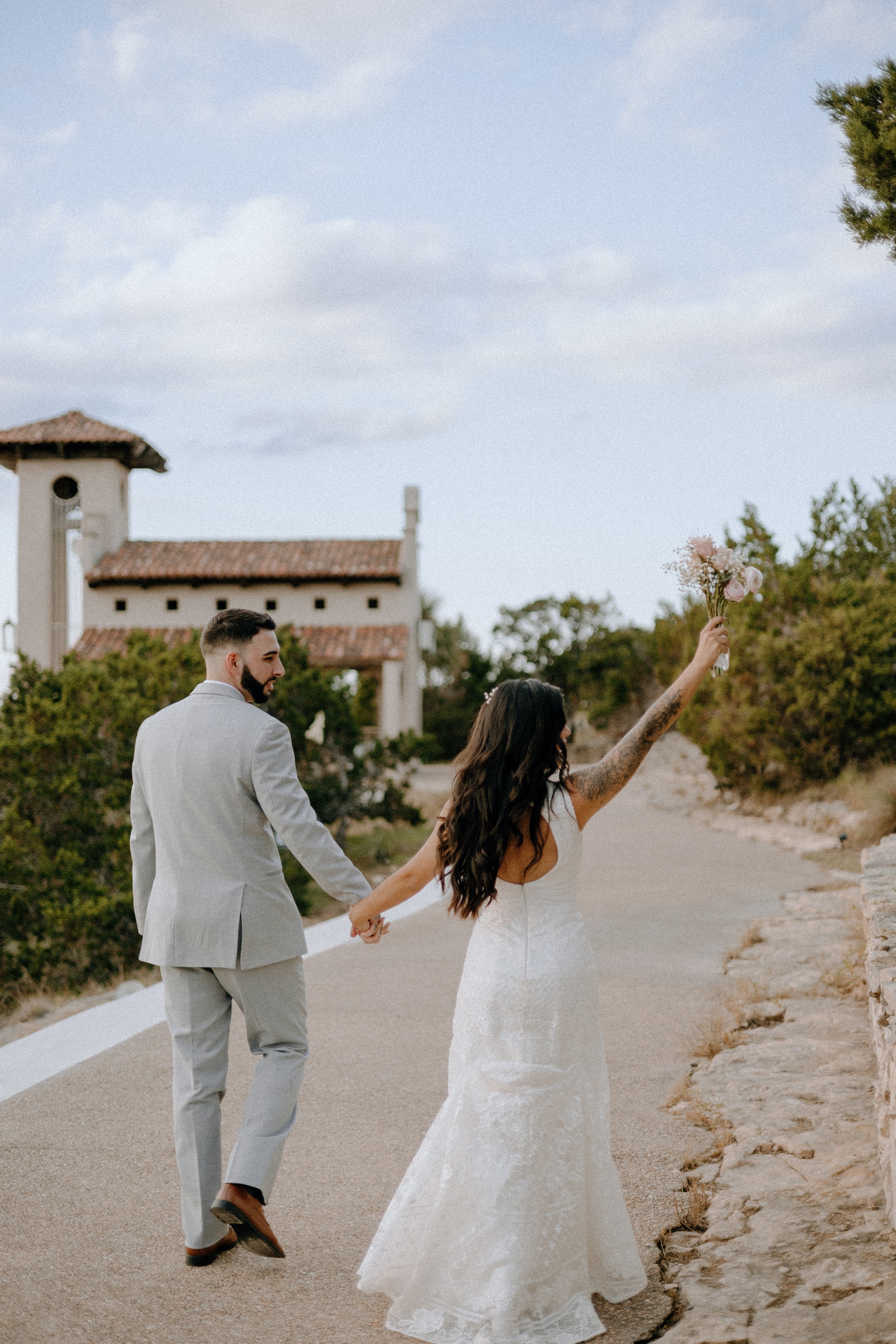 Wedding & Elopement Photography, Joyful husband and wife walking towards their outdoor wedding ceremony, wife cheerfully raising her hand