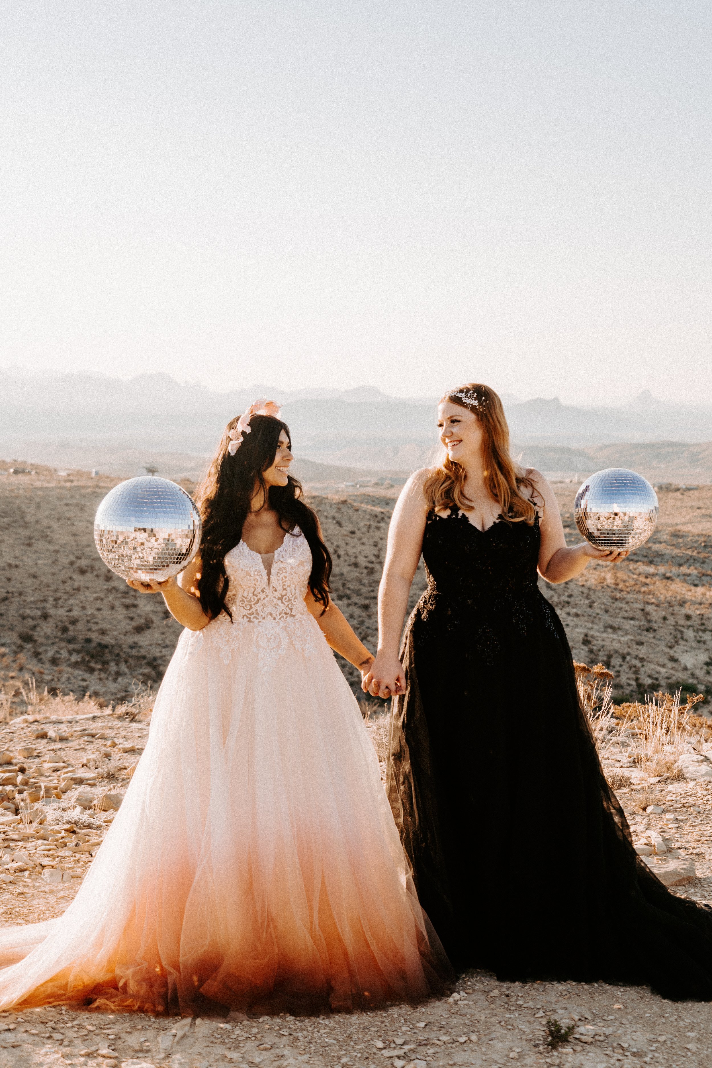 Wedding & Elopement Photography, LGBT brides holding disco balls and sharing a loving gaze in a desert setting