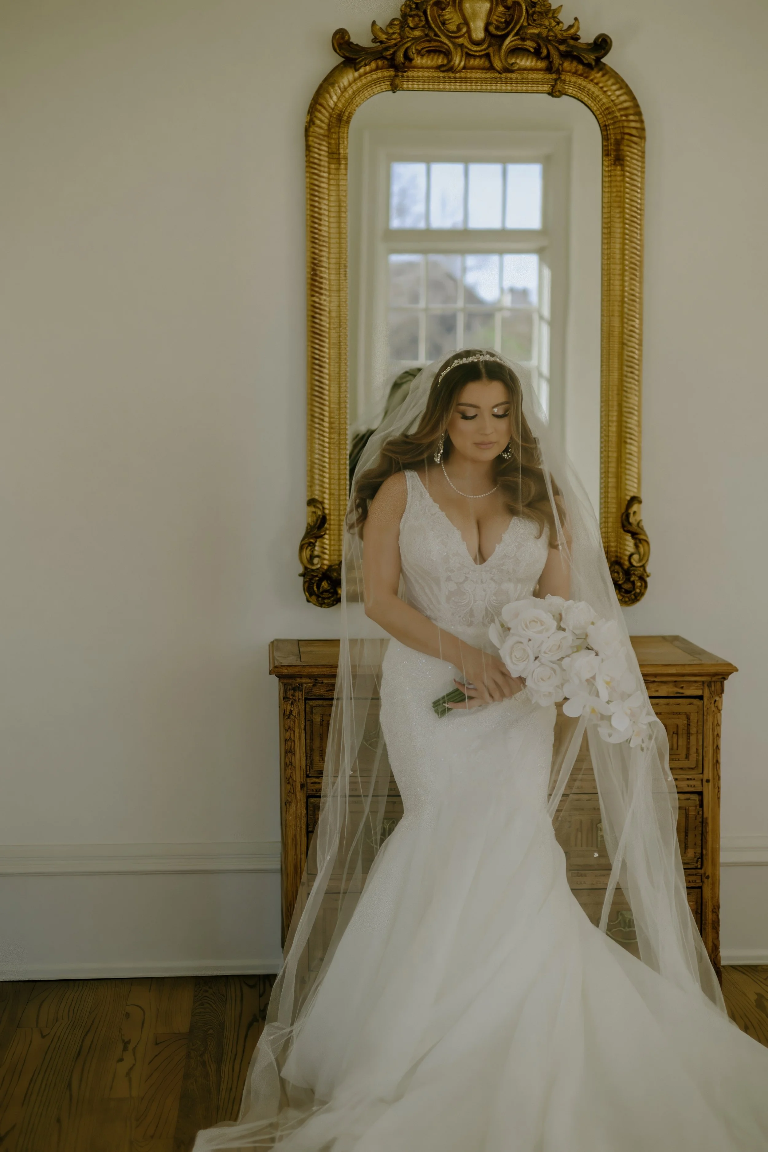 Houston & Texas Family, Couples, Newborn, Maternity, Bridal Photography – Bride seated with bouquet near chandelier, Houston white-and-gold.