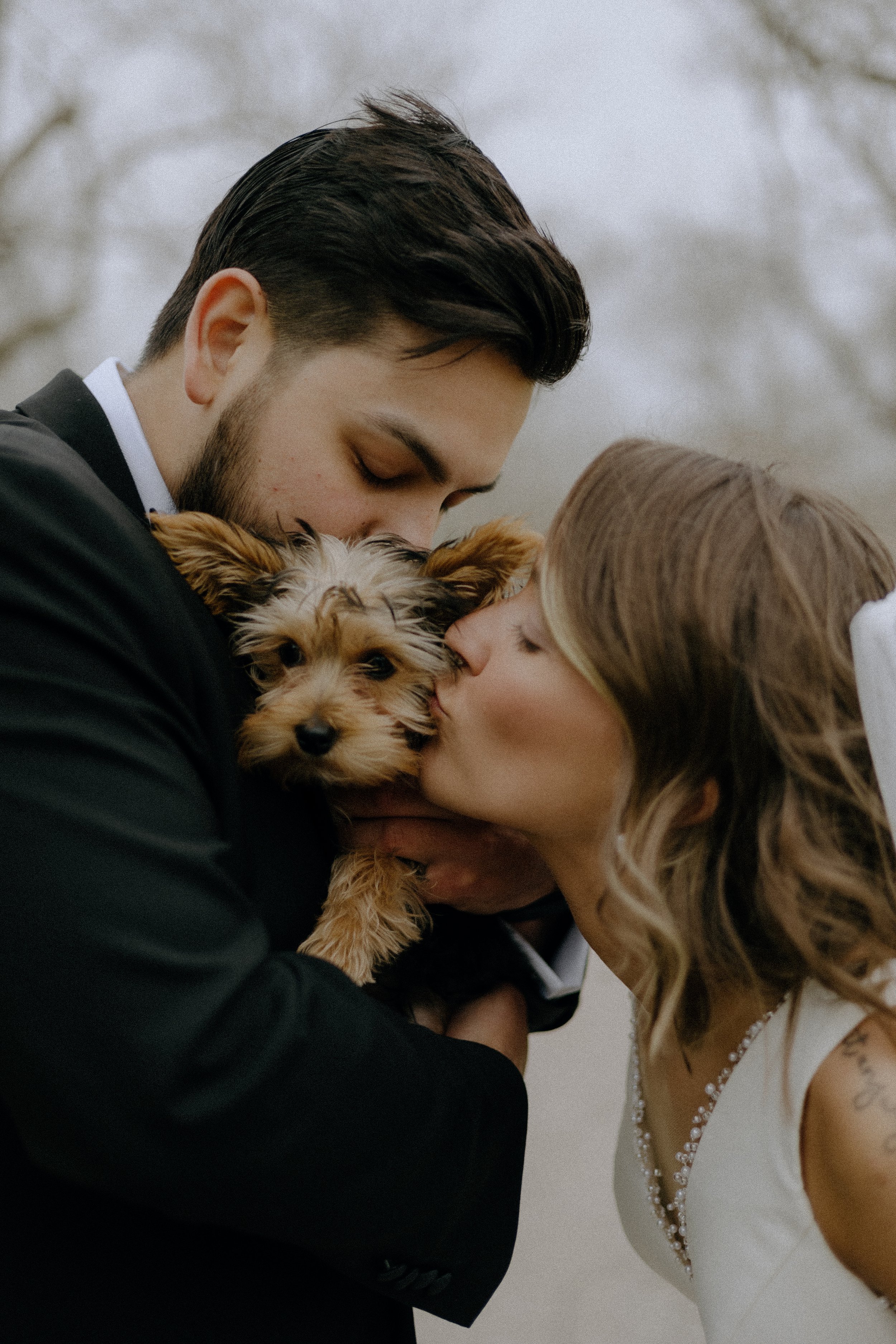 Wedding & Elopement Photography, close up of bride and groom kissing their little dog on the cheek