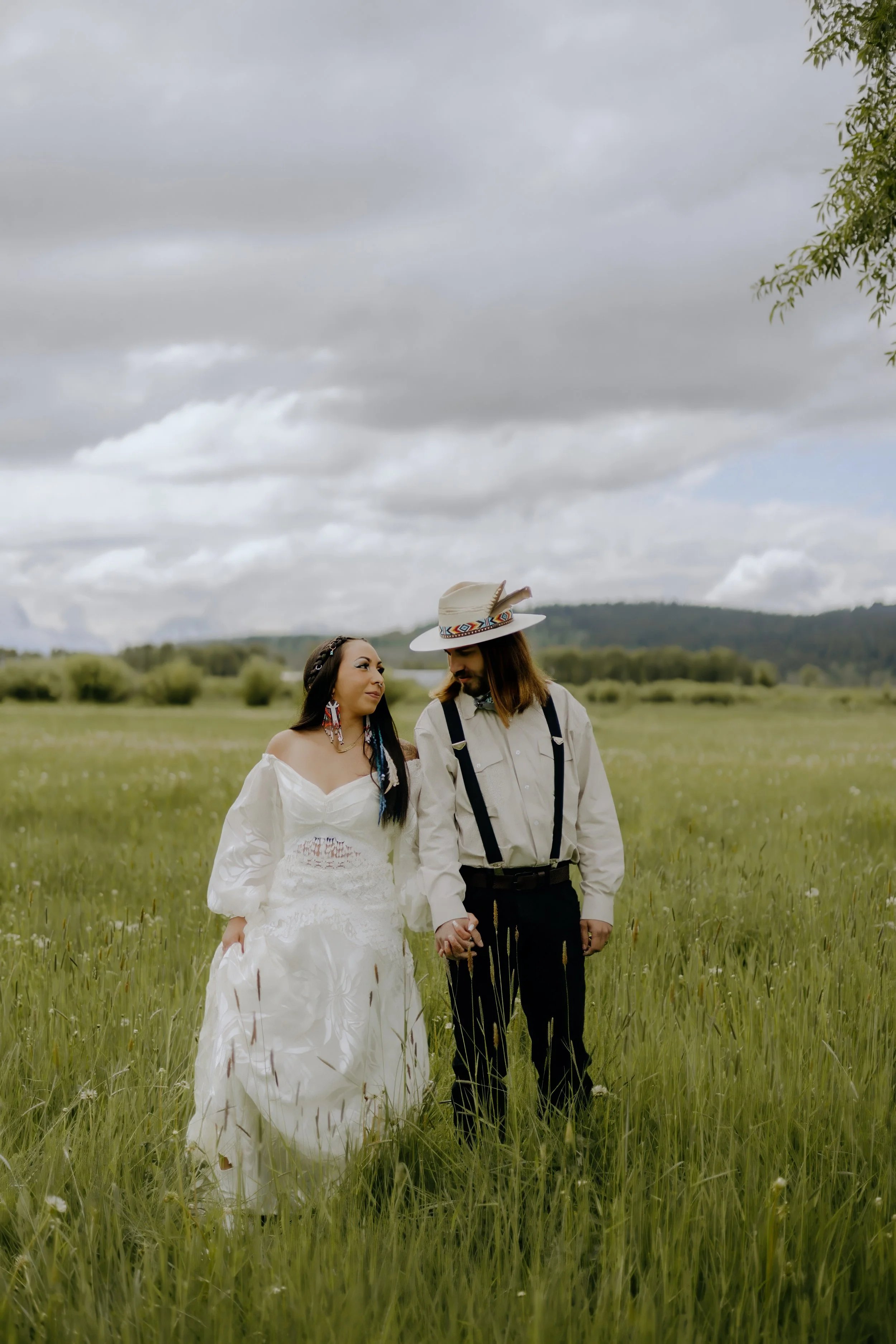 Houston & Texas Wedding & Elopement Photography – Couple standing side by side in open field at Diamond Cross Ranch with wild horses in distance.