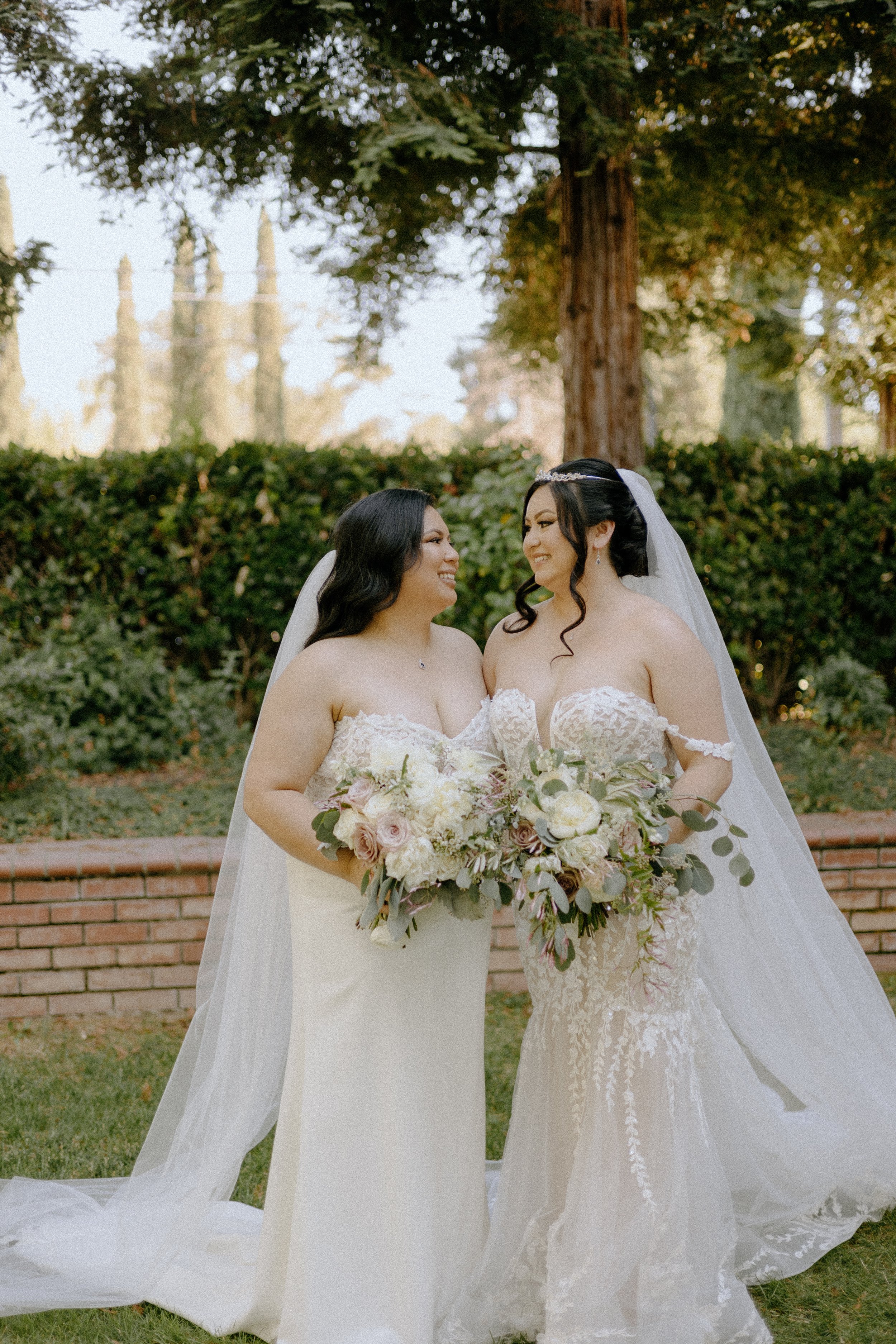 Wedding & Elopement Photography, LGBT brides deeply gazing at each other in a lush garden while holding colorful bouquets
