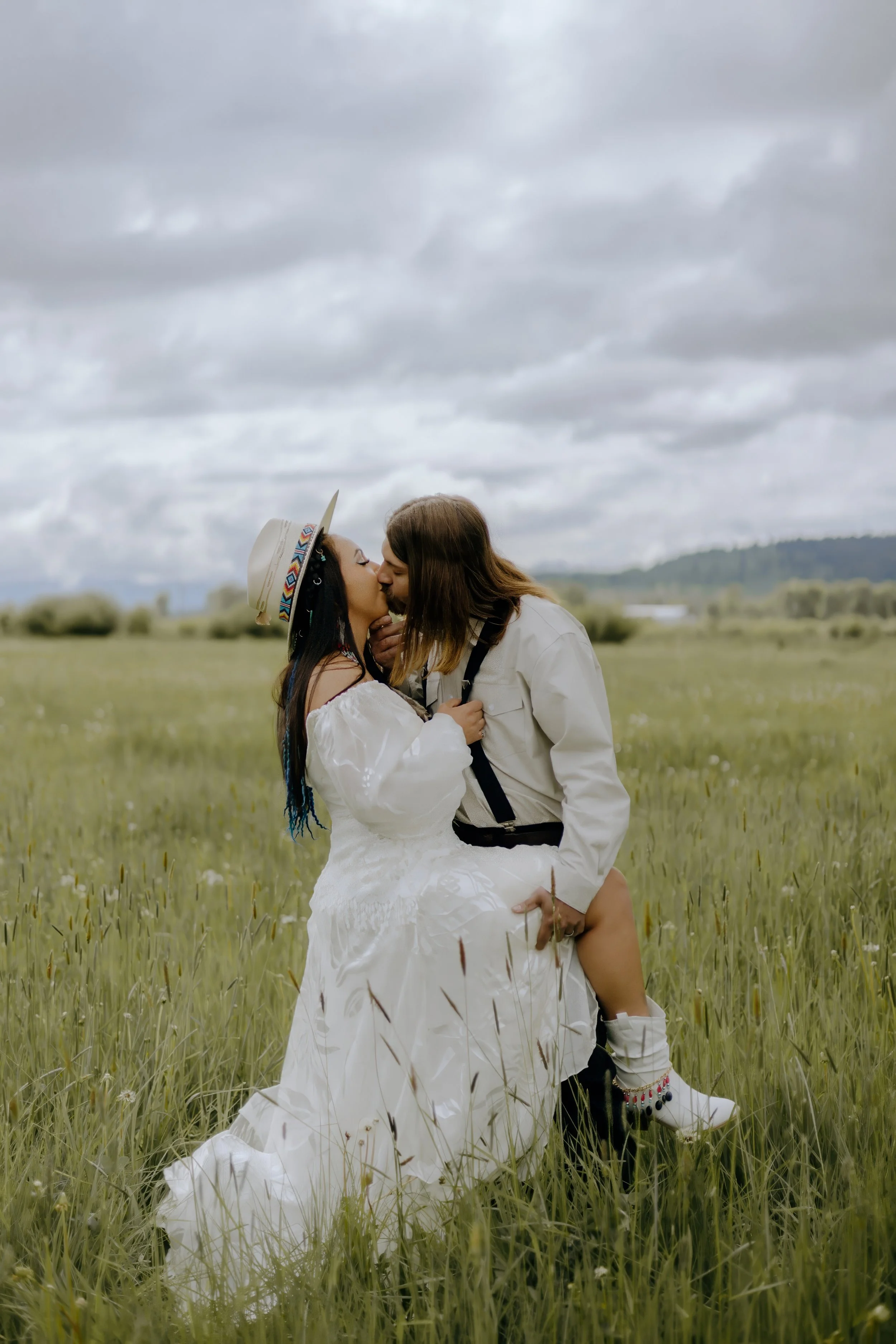 Houston & Texas Wedding & Elopement Photography – Couple kissing in grassland near grazing horses at Diamond Cross Ranch.