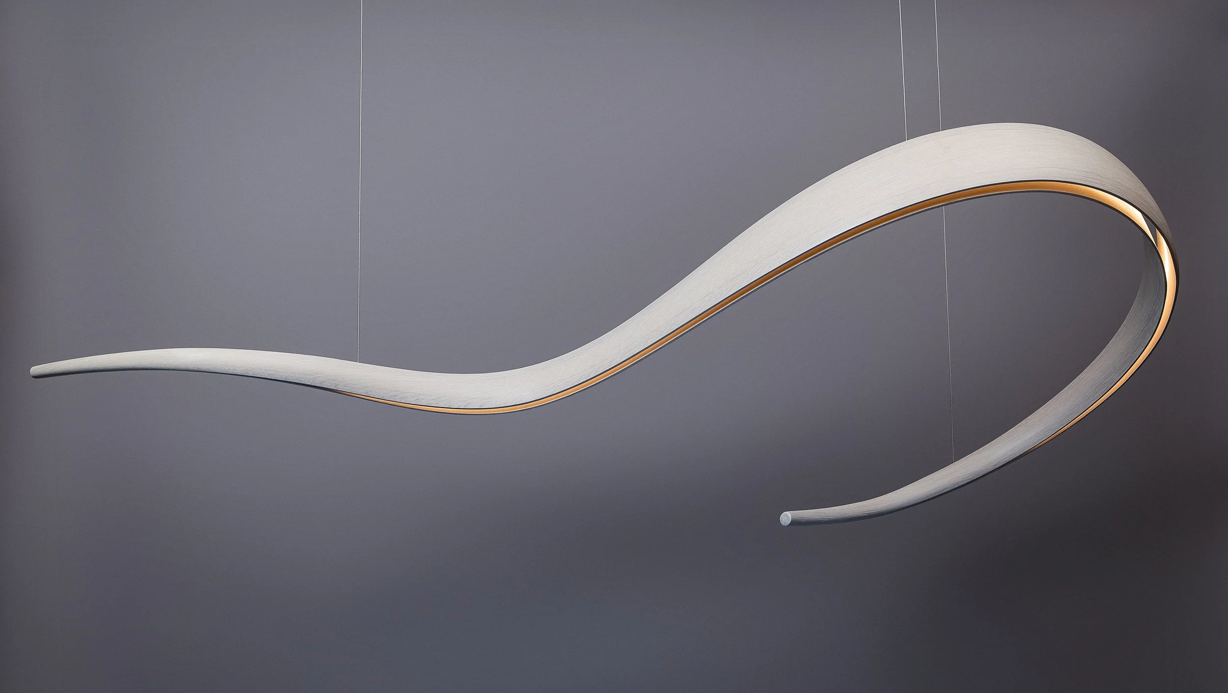 White suspended architectural lighting sculpture with flowing curved form and integrated illumination by Adam Bentz.
