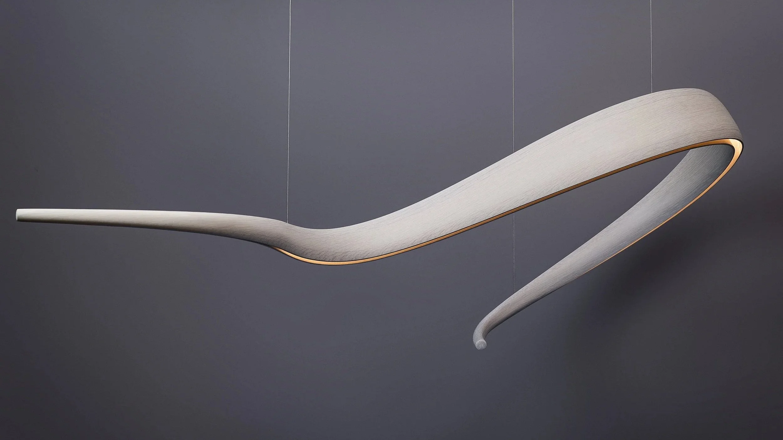 Suspended sculptural wood lighting with composed illuminated curved form.
