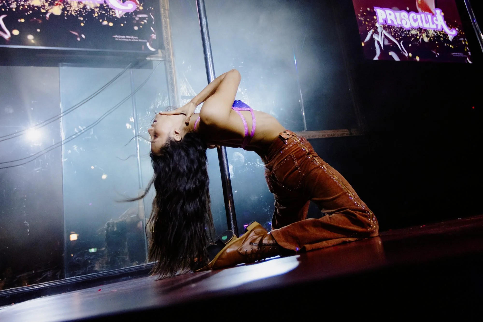 Performer in a purple top and studded brown pants doing a backbend during a stage show at Centrefold Lounge