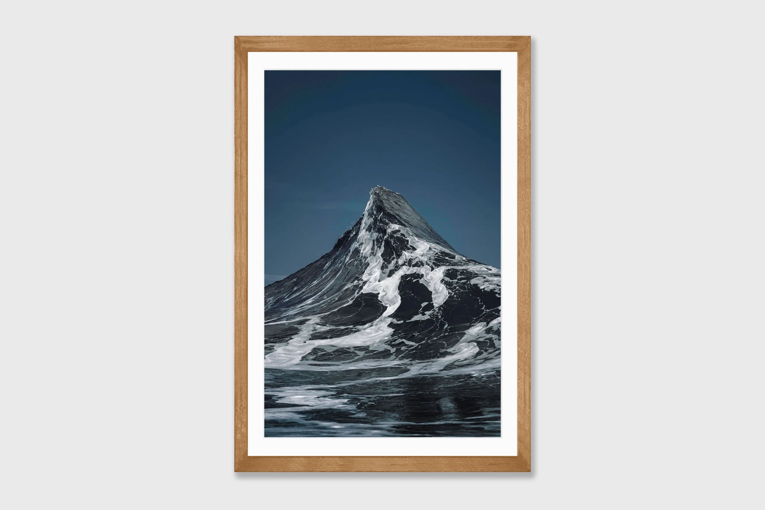 Two ocean waves crashing together forming a peak shape resembling the Matterhorn mountain, captured in dramatic coastal light.