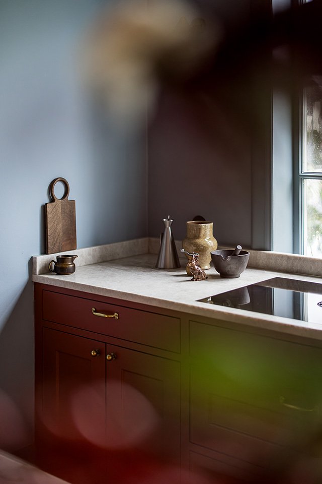 Platsbyggt klassiskt lantkök i modern utformning och funktion. Modernt rundade former matchas med marmorbänk och köksinredning i djup varm röd nyans. Till duvblå väggar.