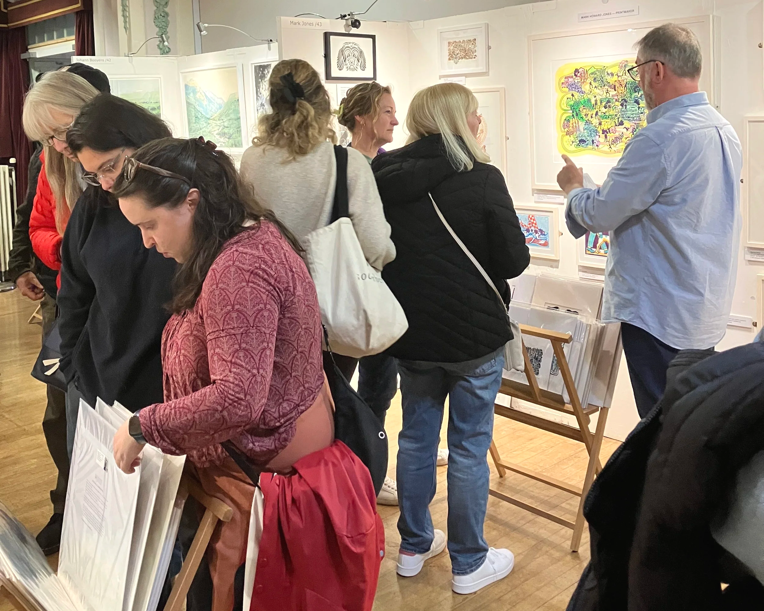 Artist discussing printmaking process with visitors at art fair