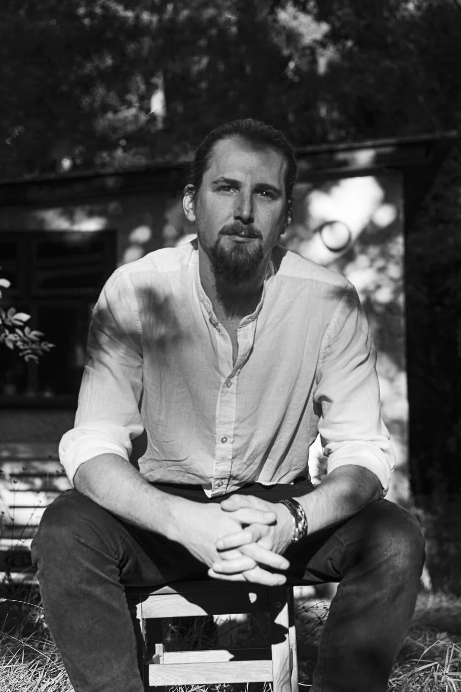 Szymon Olszowski in white shirt sitting outdoors, black and white photo