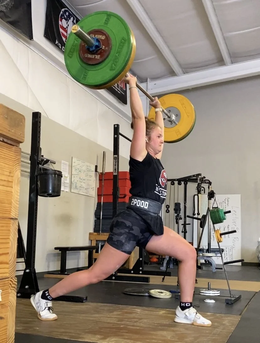 a woman doing a barbell split jerk