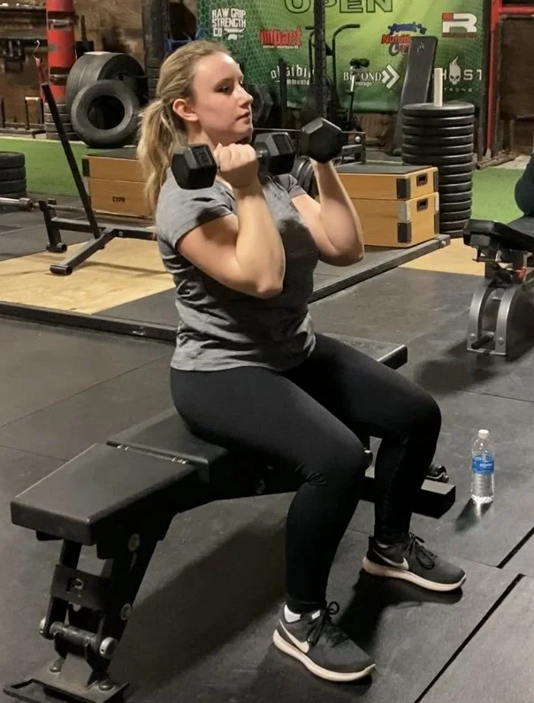 a woman with dumbbells doing a seated press