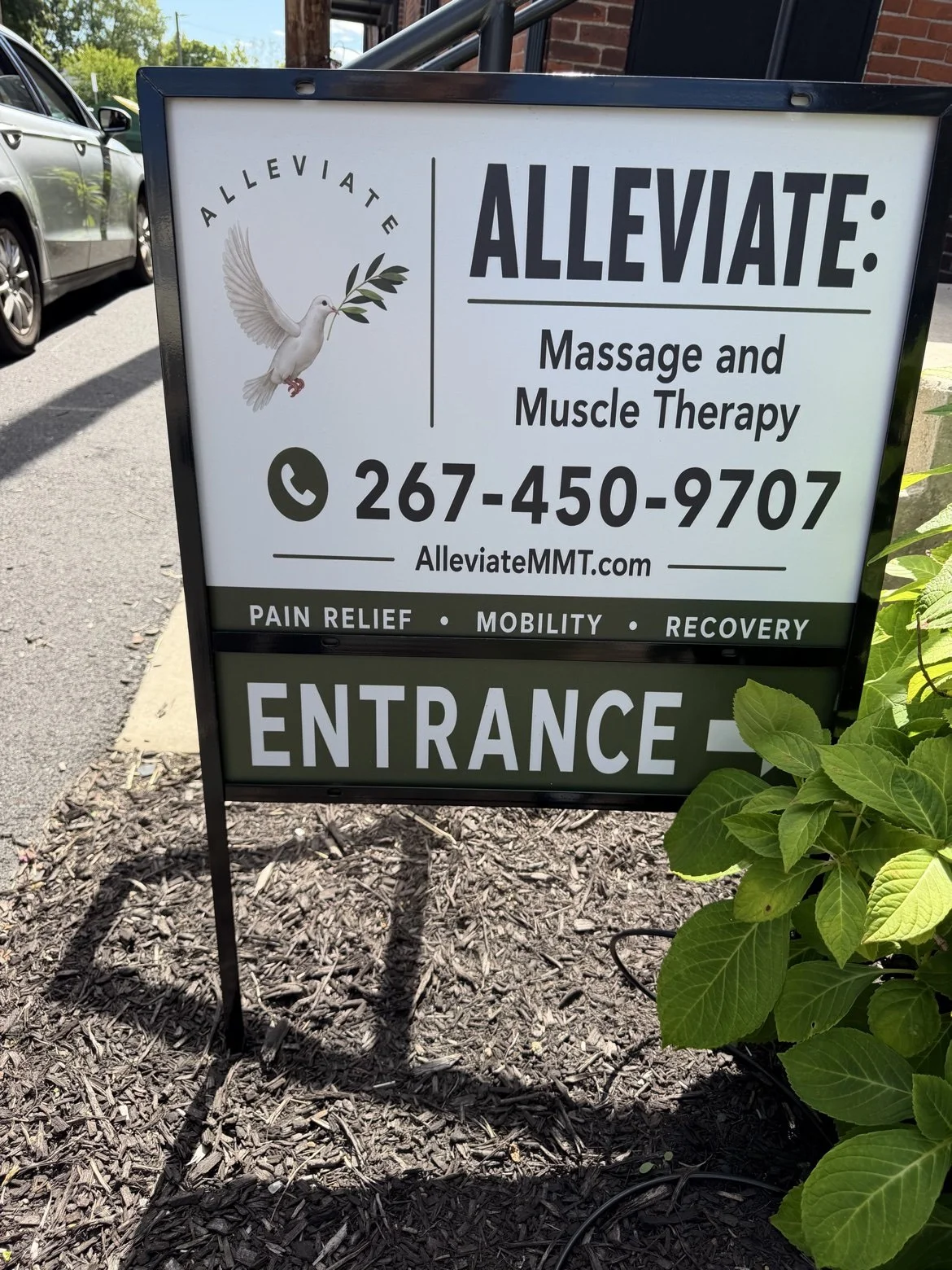 Close-up of the ALLEVIATE entrance sign showing the phone number 267-450-9707