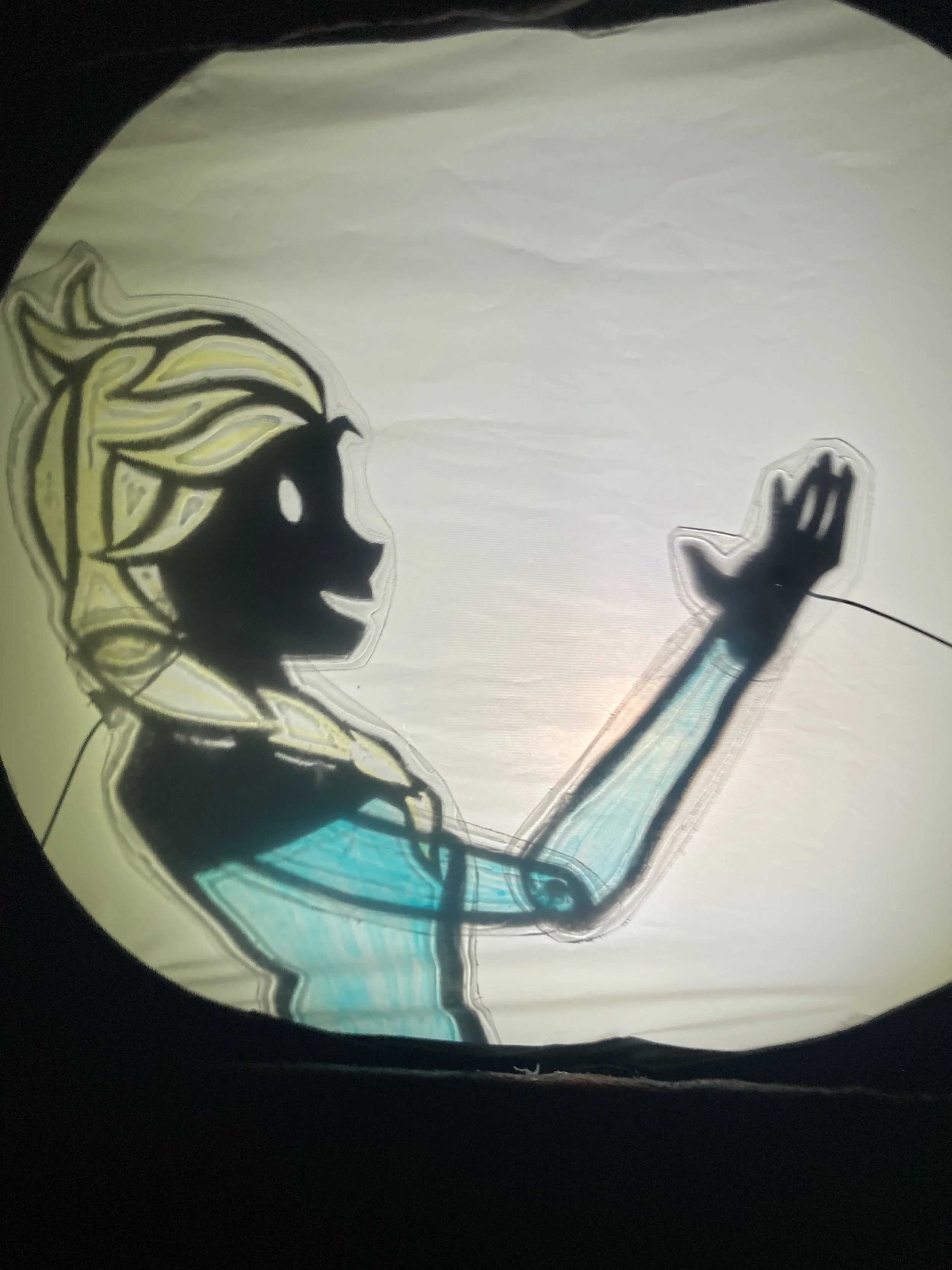 Alt Text:A shadow puppet princess with blonde plaited hair and a blue dress reaches out
