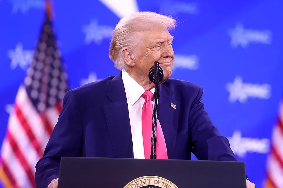 President Trump standing at a podium with American Flags in the background