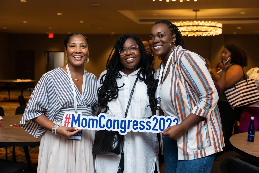 Three attendees smiling together at Mom Congress