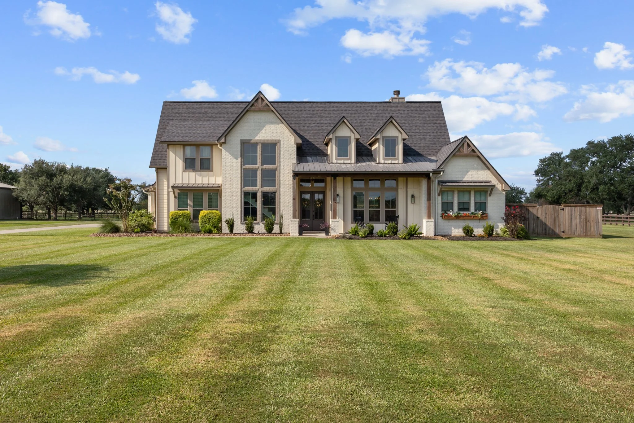 Large suburban house with a well-maintained lawn under a partly cloudy sky.