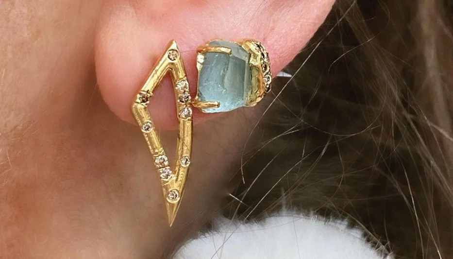 diamond and gold statement earring and aqua hued gemstone stud earring in woman's ear
