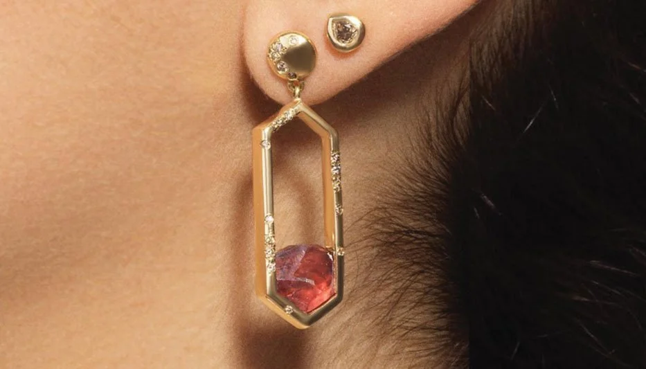 gold gemstone earring with red stone worn on a woman's ear
