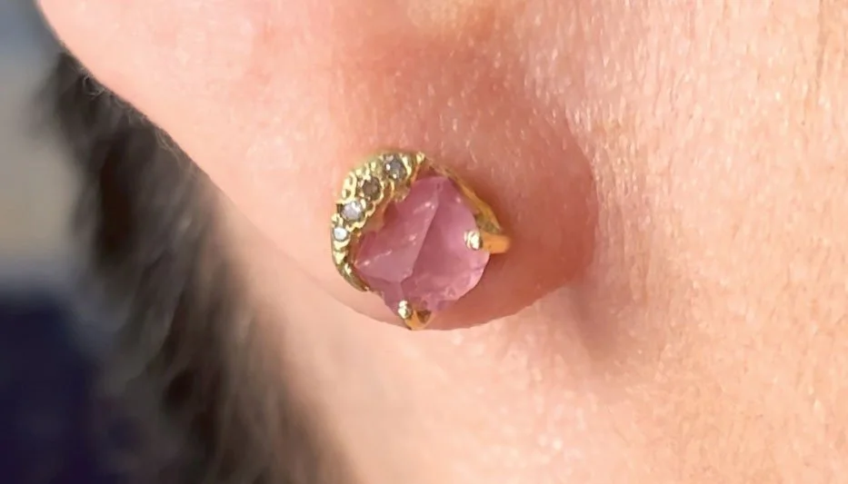 pink gemstone stud earring worn on woman's earlobe