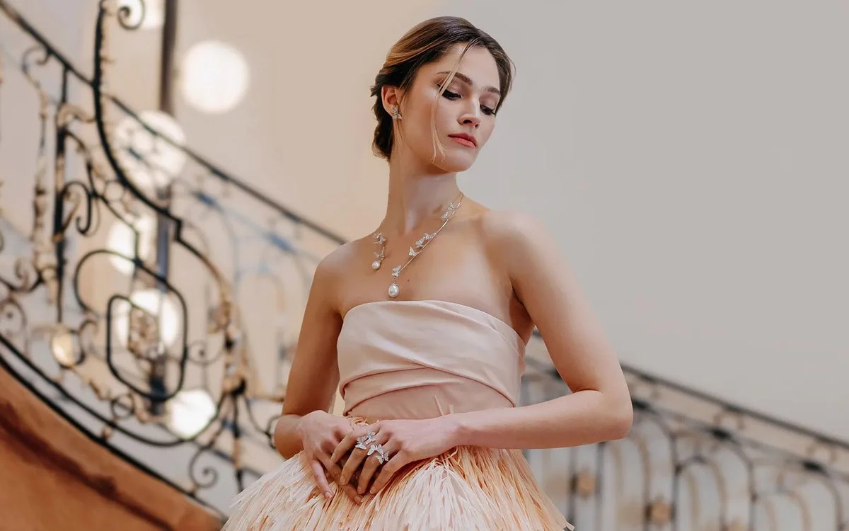 Woman in cocktail dress wearing pearl and diamond butterfly jewelry