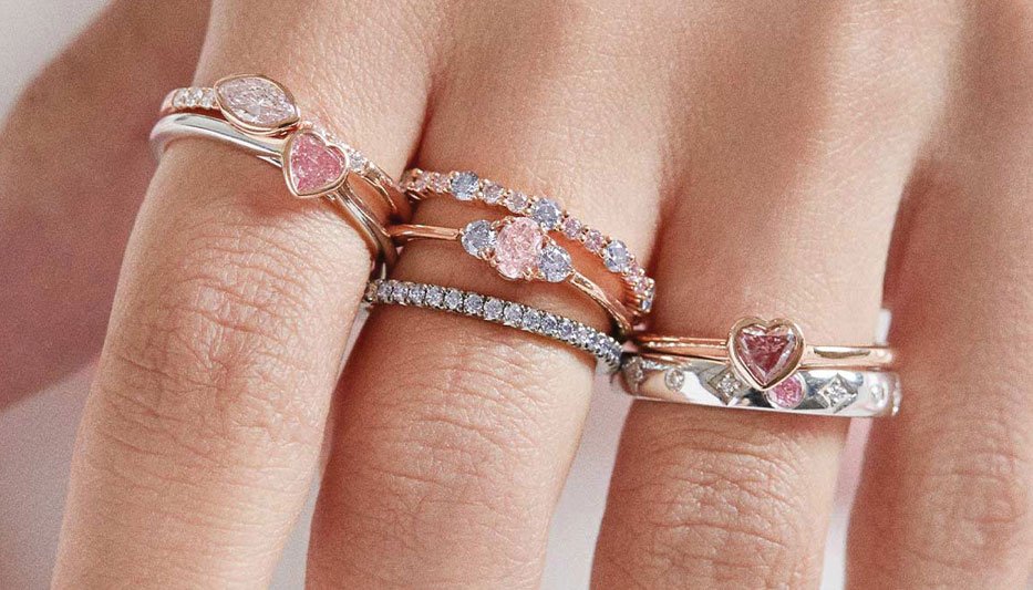 pink diamond stacking rings worn on woman's hand