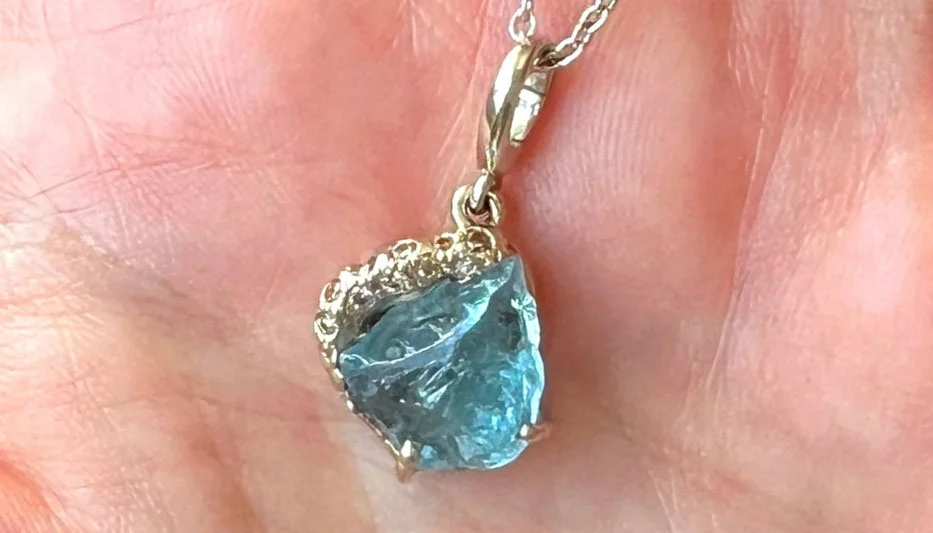 white gold layered necklace featuring an aquamarine on a hand