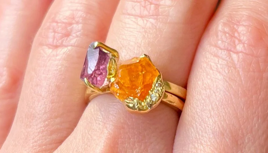 two warm hued colored gemstone rings worn stacked together