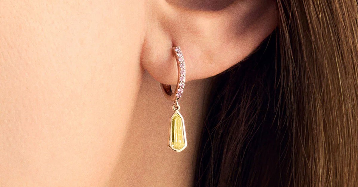 yellow-and-pink-diamond-drop-huggie-hoop-earrings-on-womans-ear.jpg