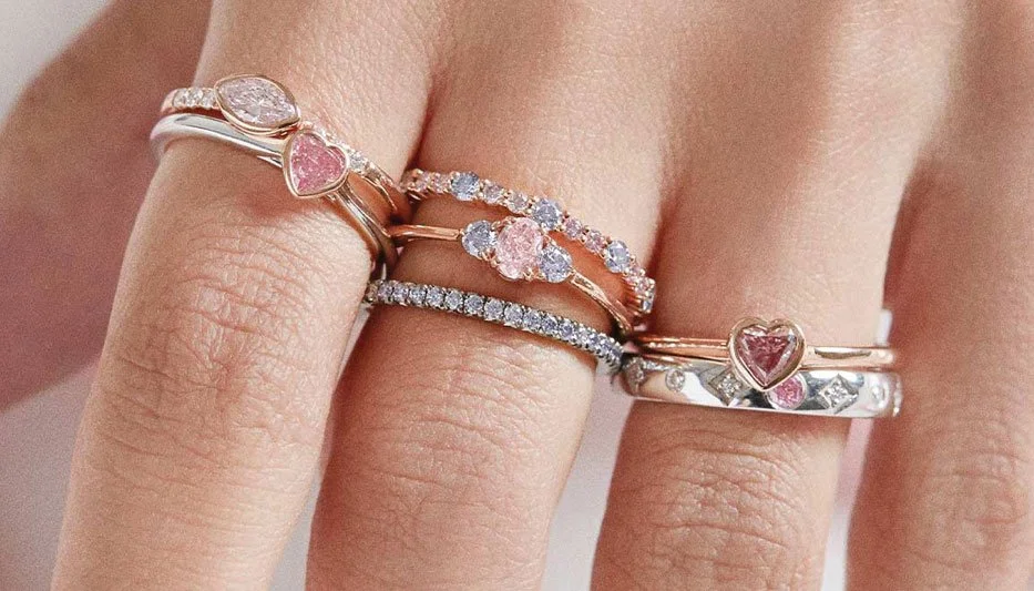 pink diamond stacking rings on woman's fingers