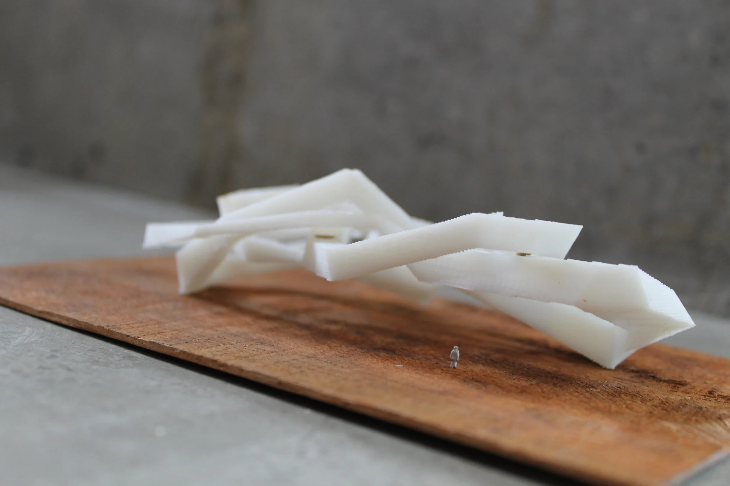 An architectural model of a white, knotted building structure. 