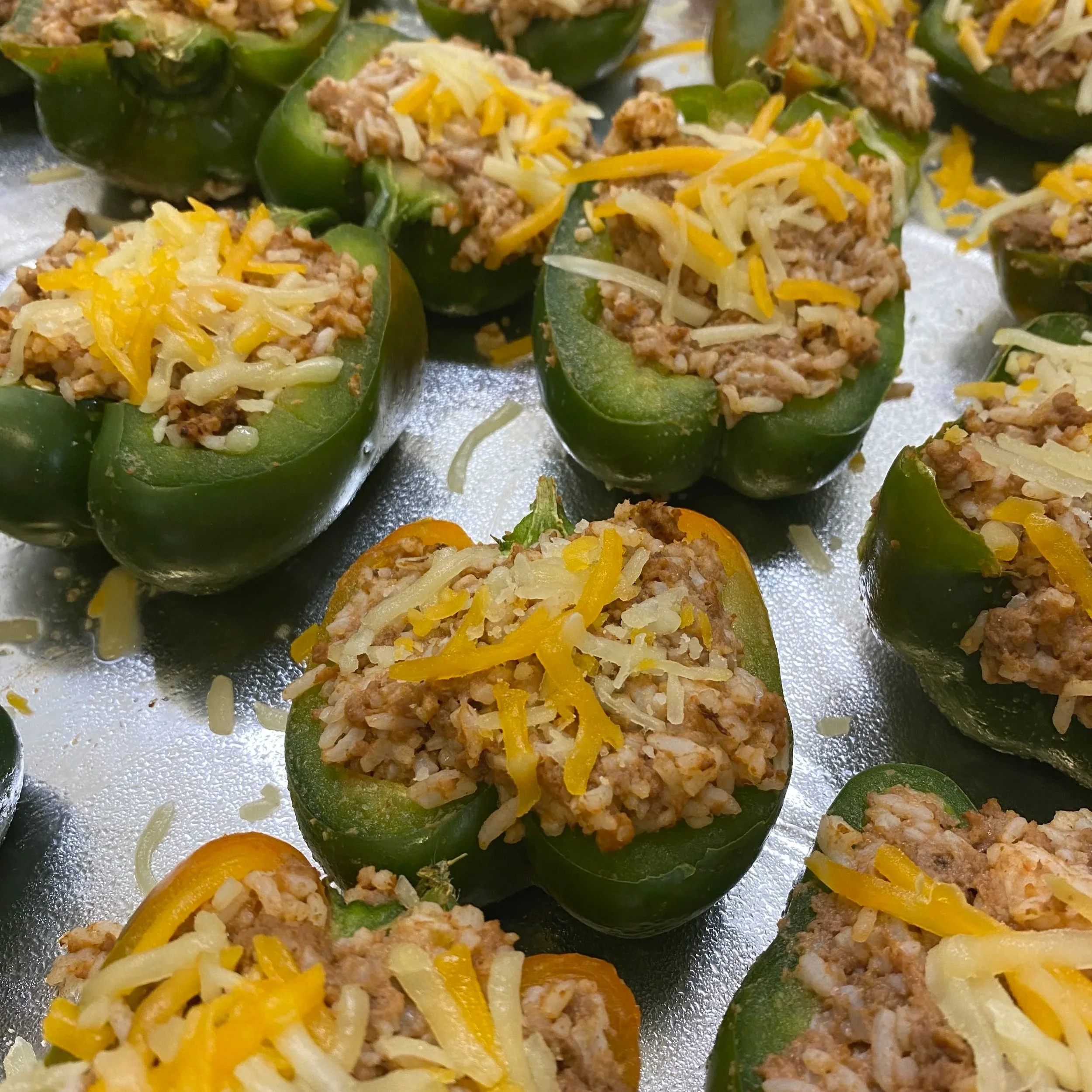 Green bell peppers halved and filled with ground meat, rice, and shredded cheese.
