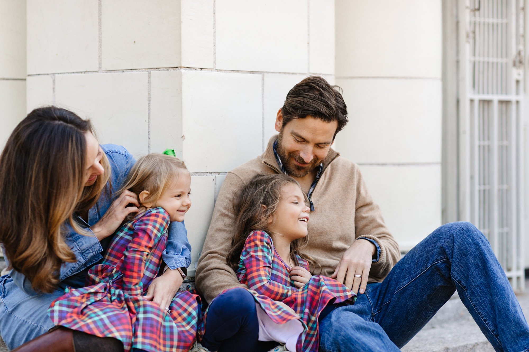 Family smiling and sitting outdoors, wearing casual clothes