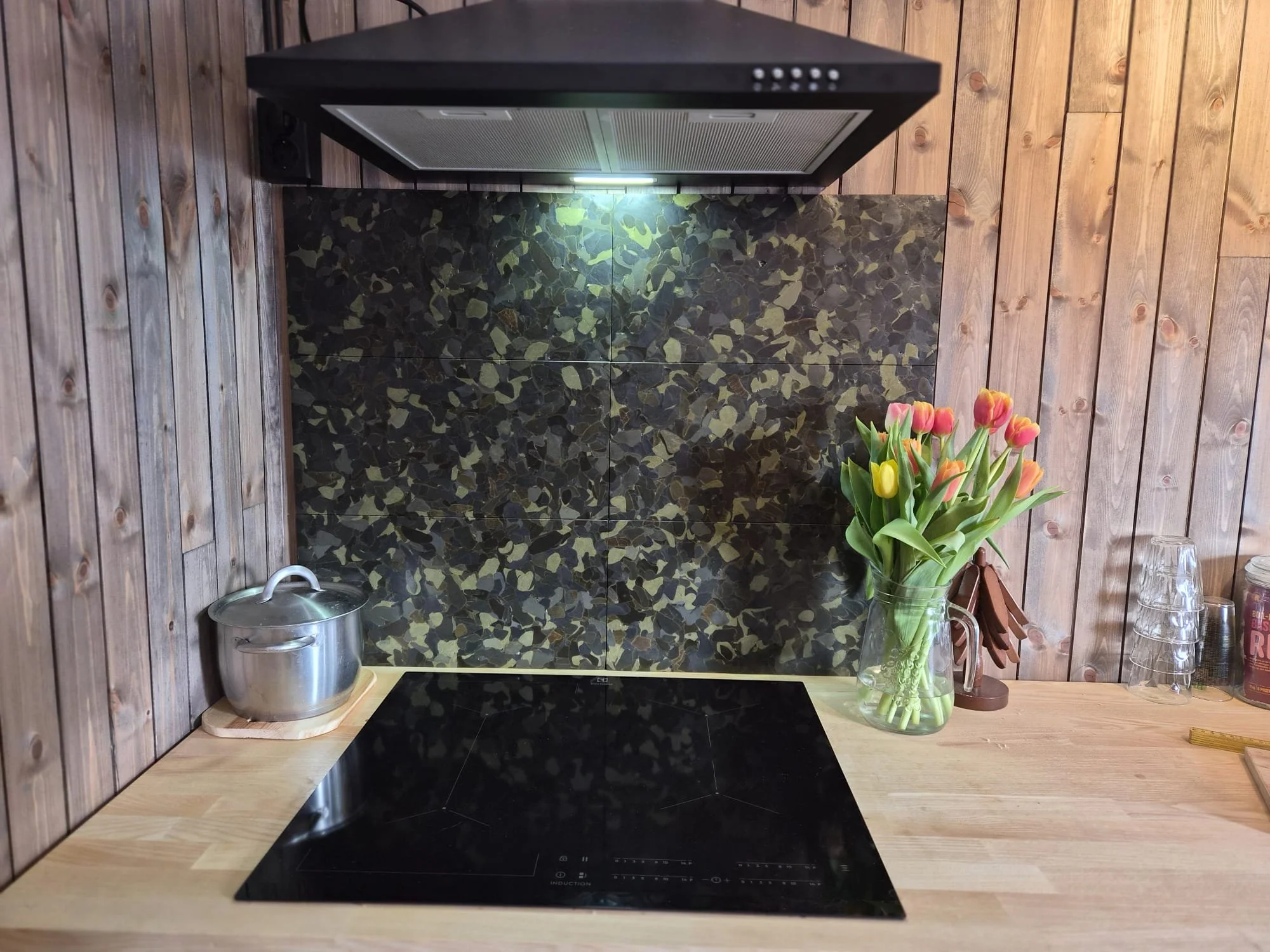 a kitchen scene featuring a brown kitchen splashback made from discarded glass bottles