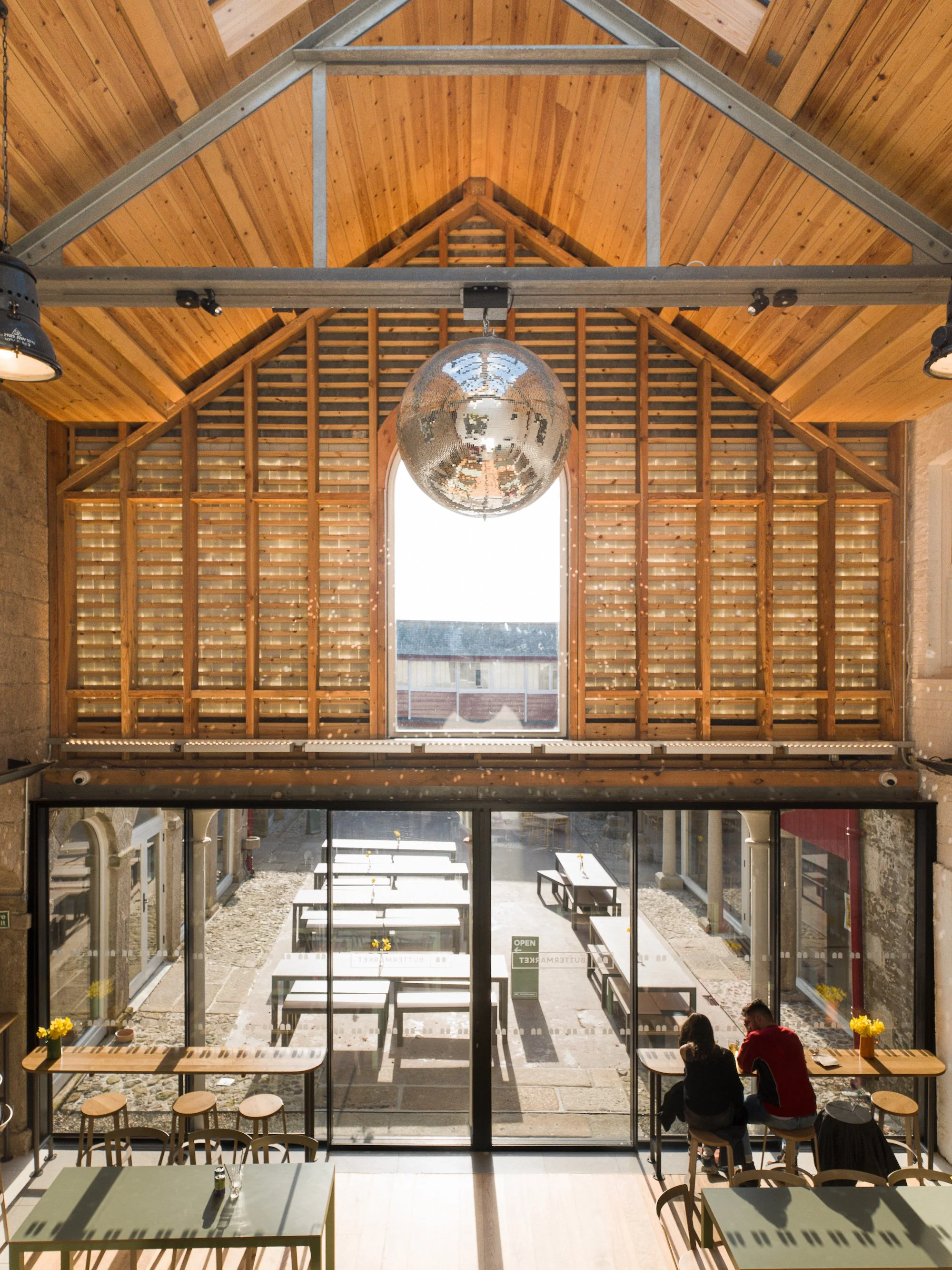 Interior view of the recycled glass at the Buttermarket, showing a window framed by wooden structures supporting the glass tiles and slate. The image highlights the light penetration through the glass tiles. Photo: Claire Fear