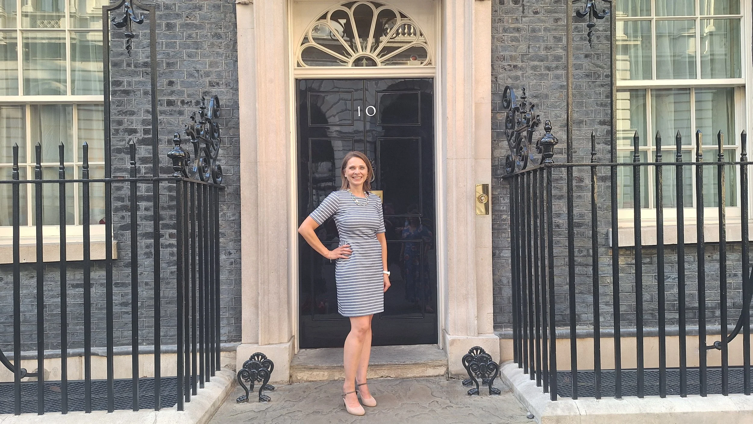Tyra Oseng-Rees standing in front of 10 Downing Street, London, with her hand on her hip, smiling.