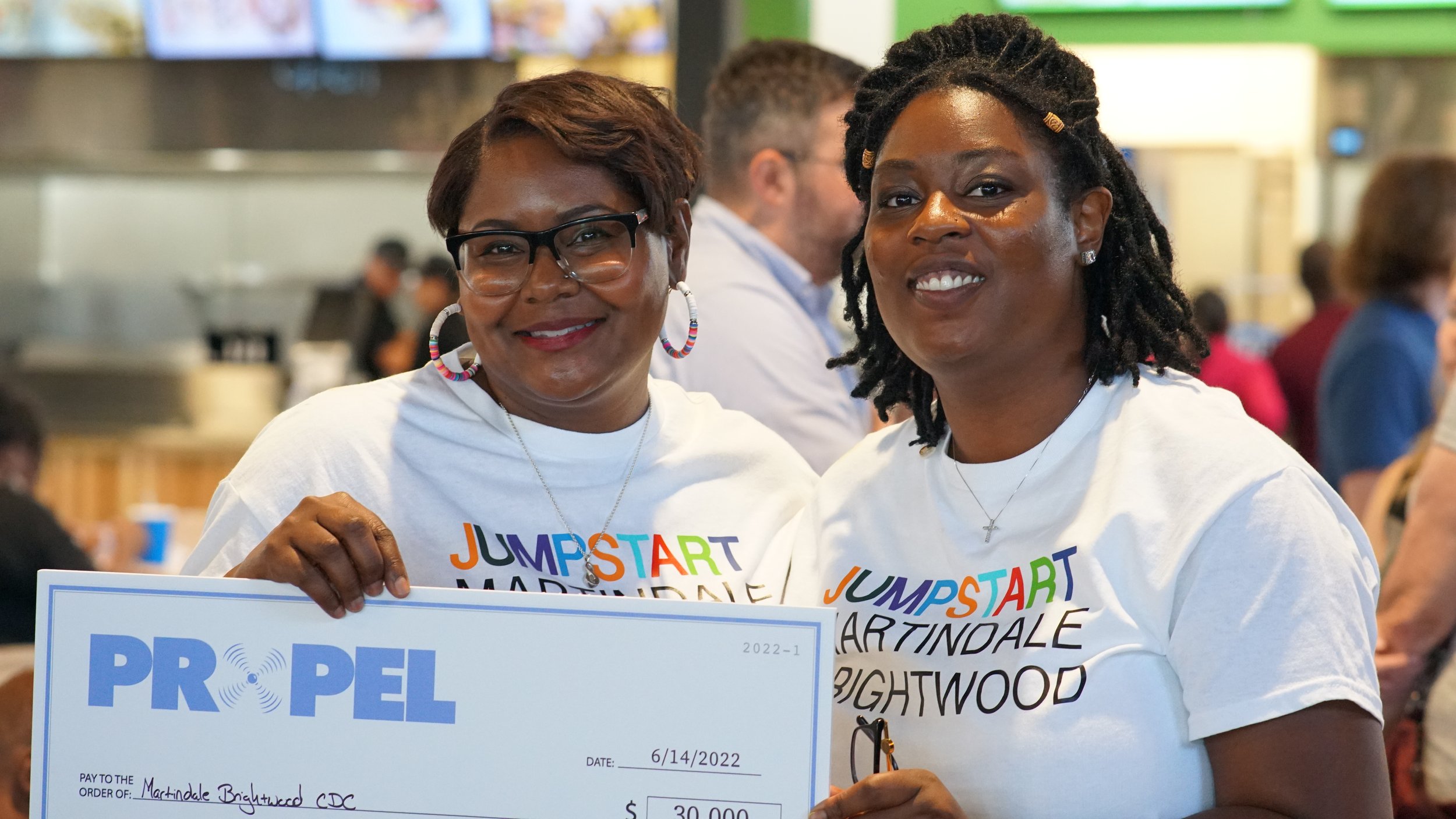  Dr. JoAnna Brown (left) and Joi Harmon of Martindale Brightwood Community Development Corporation pose with a check after winning Propel, a United Way pitch competition, June 14, 2022, at The AMP at 16 Tech in Indianapolis. 