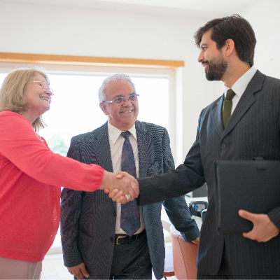 Business man and woman shaking hands completing a deal. Pastor in the middle smiling.