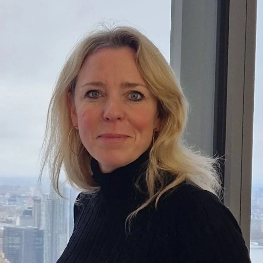 Annabel is a white woman with long blonde hair, she wears a black polo neck and smiles to the camera.