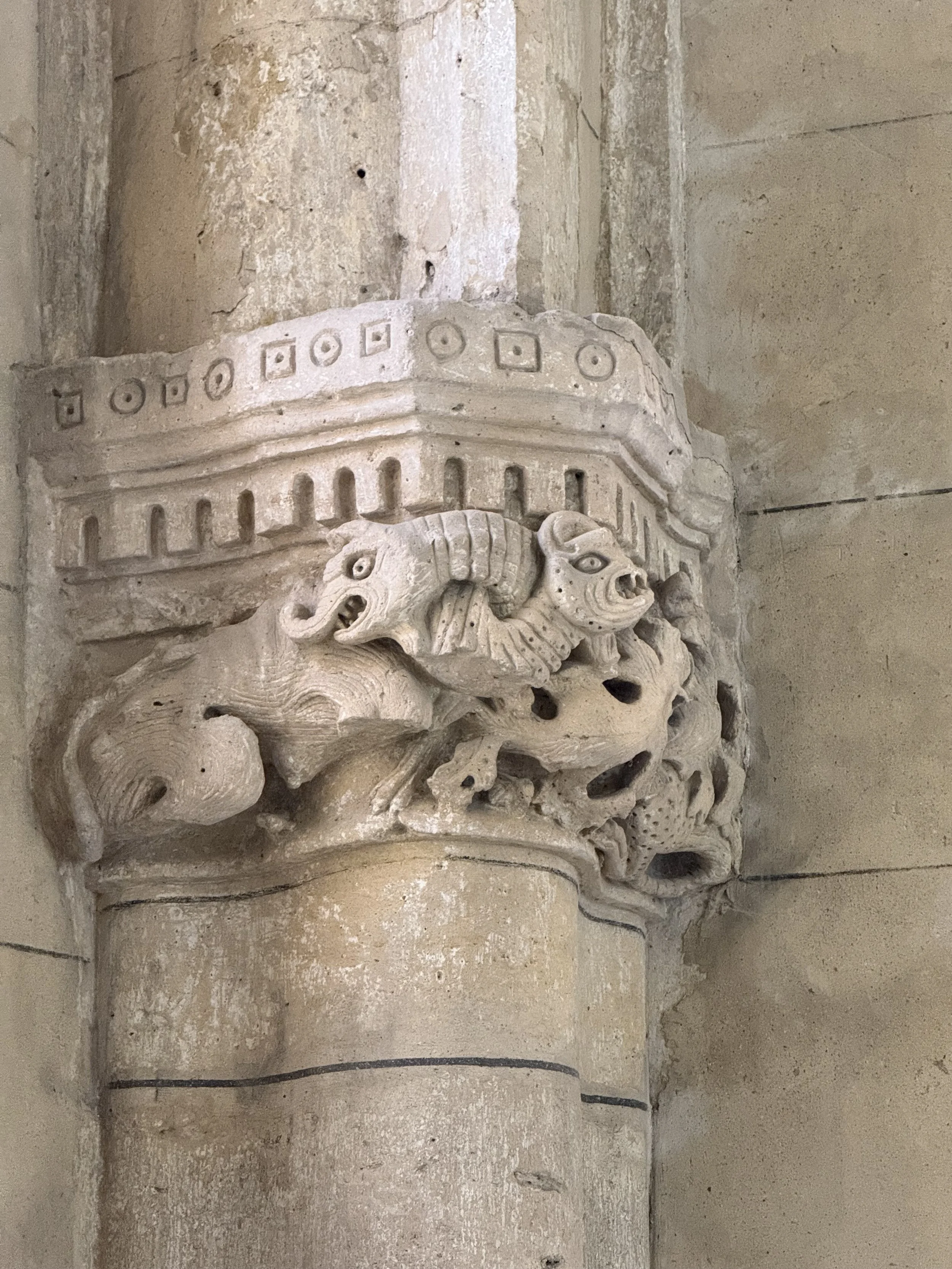 Ancient stone carving featuring a fierce mythological creature with a lion-like face, curled mane, and open mouth, embedded in a stone wall.