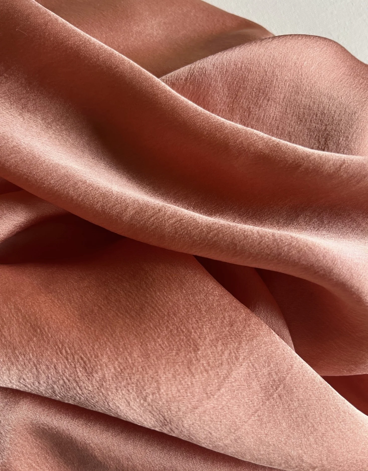 Close-up of peach-colored satin fabric with soft folds and smooth texture