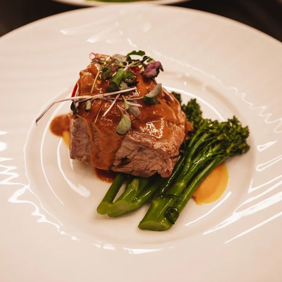 Grilled steak served with broccolini and sauce from LM Catering.