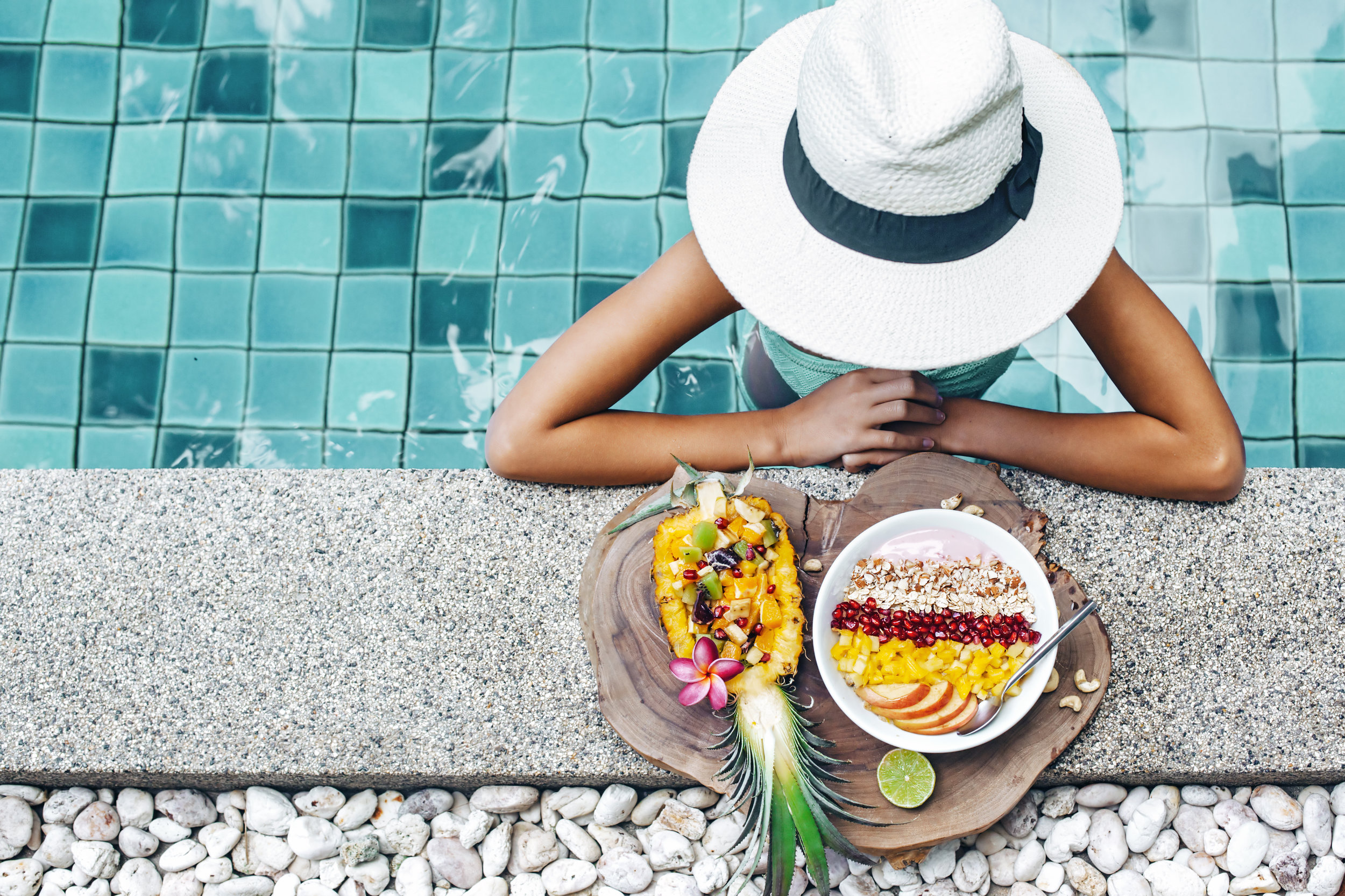 pineapple and woman by pool with white hat.jpeg