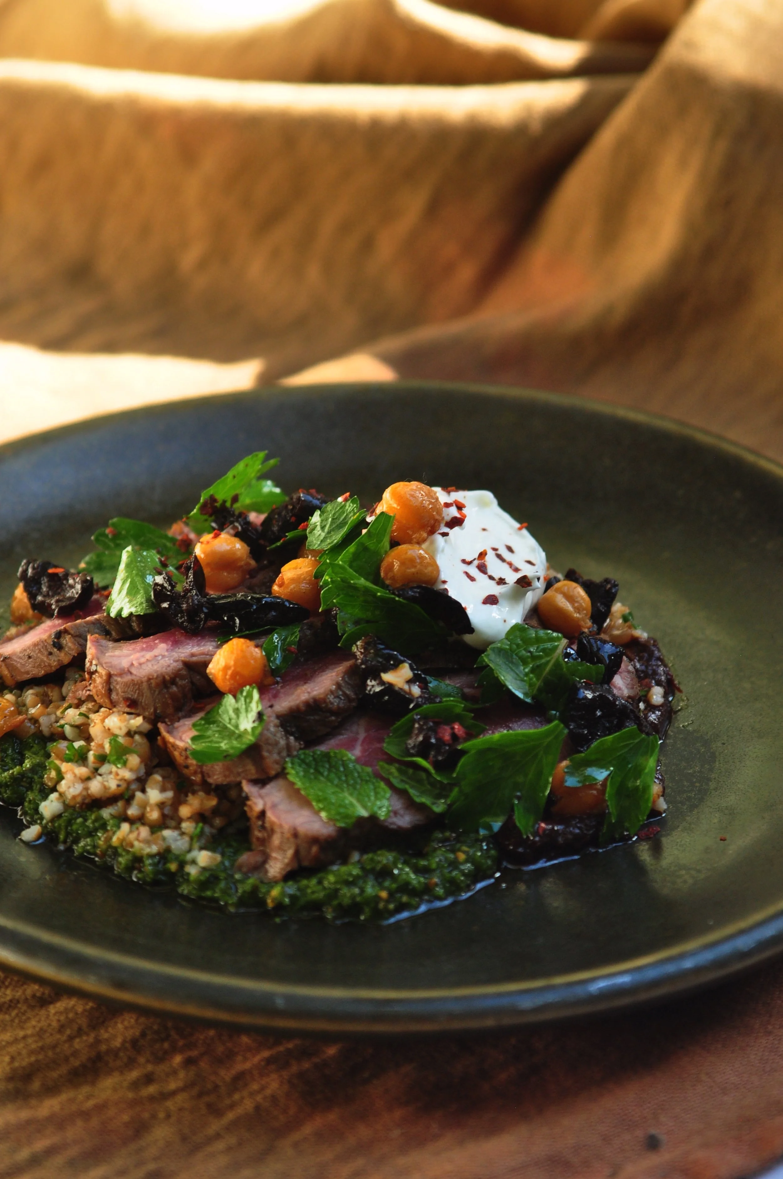 braised liberty duck, red wine red cabbage, grilled bacon & crème fraiche on an orange fabric background