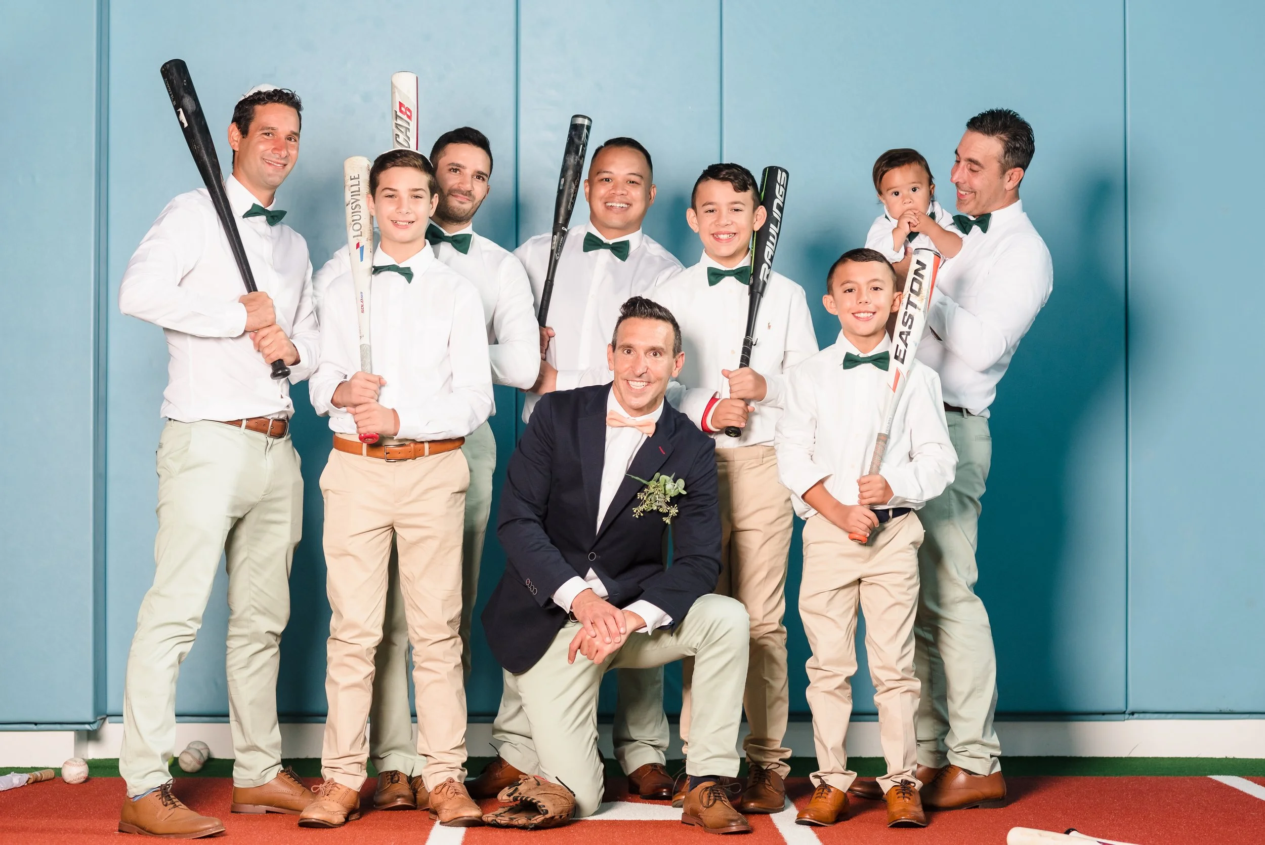 Groomsmen and groom pose at a batting cage