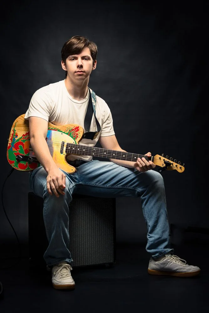 high school senior boy sitting on an amp with electric guitar